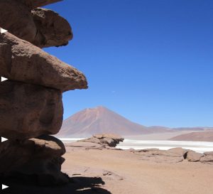 The ignimbrite (same unit as image above) is composite, consisting of overlapping flow units (white arrows) separated by subtle changes in pumice and crystal content, the contacts weathering out as apparent horizontal joints. About 5 m of section in this view. In the background, a nicely preserved Middle Miocene volcanic cone, plus a peekaboo view of Salar LaGrande.