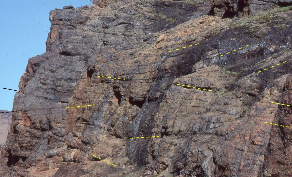 Like the preceding image, successive trough crossbeds in this unit are discordant (dashed lines), but here the bedforms developed in much coarser grained channel sediment. Individual crossbeds are much larger – up to 1.5 m thick and laterally more extensive. Each crossbed set represents a stage in the migration of large 3D gravel bars in a low sinuosity (braided) channel. Flow velocities in these channels would have been significantly greater than in the sand-dominated channels illustrated in the preceding photo. Mid-Jurassic Bowser Basin, northern British Columbia.