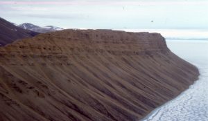 Talus fan colluvium sourced from bluffs of Eocene conglomerate (Buchanan Lake Fm.), Emma Fiord, Ellesmere Island. Depositional mechanisms are primarily mass wasting (rock fall and slide) and slope wash during the Arctic spring thaw. The transfer of colluvium to the shoreline will produce significant improvements in sorting and stratification.