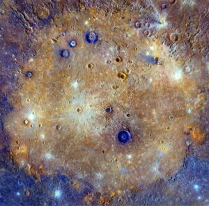Enhanced colour mosaic of Caloris Basin, Mercury. The crater-filling lavas are pockmarked by younger impacts. The blue colour centres of some of the younger craters indicate lower albedos than the surrounding lava plain, albedos that are similar to rock materials beyond Caloris’ rim – the inference is that the small craters provide a window to bedrock beneath the lavas. Lava thickness is therefore equivalent to crater depth, in this case 2.5 – 3.5 km. Image Credit: NASA/Johns Hopkins University Applied Physics Laboratory/Carnegie Institution of Washington.