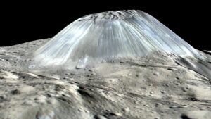 A simulated perspective of Ahuna Mons on dwarf planet Ceres, based on multiple images taken by DAWN spacecraft. The images were taken at an altitude of 385 km. Vertical scale exaggerated 2 X. The actual height of the cone is 4000 m, and its base 20 km wide. The geologically young flanks are devoid of craters. Bright streaks are remnants of ice slurries that cascaded down the flanks. Image credit: PIA20915 NASA/JPL-Caltech/UCLA/MPS/DLR/IDA