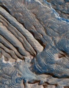A 3D rendering of remarkably regular layering of sediment in an unnamed crater in Arabia Terra region, from a stereo pair of images taken by the HiRISE camera on Mars Reconnaissance Orbiter (NASA, Feb. 2007). The field of view is about 2 km wide, and layer thickness is estimated to average 10 m. The prominent stair-step topography for each layer corresponds to colour differences within each layer, that probably are associated with differences in composition and mechanical strength. The succession dips right. It is cut by numerous faults. Image Credit: NASA/JPL-Caltech/University of Arizona, PSP_002733_1880